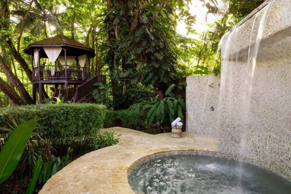 Outdoor waterfall spa shower and soaking pool surrounded by tropical forest at Zoëtry Marigot Bay St. Lucia.