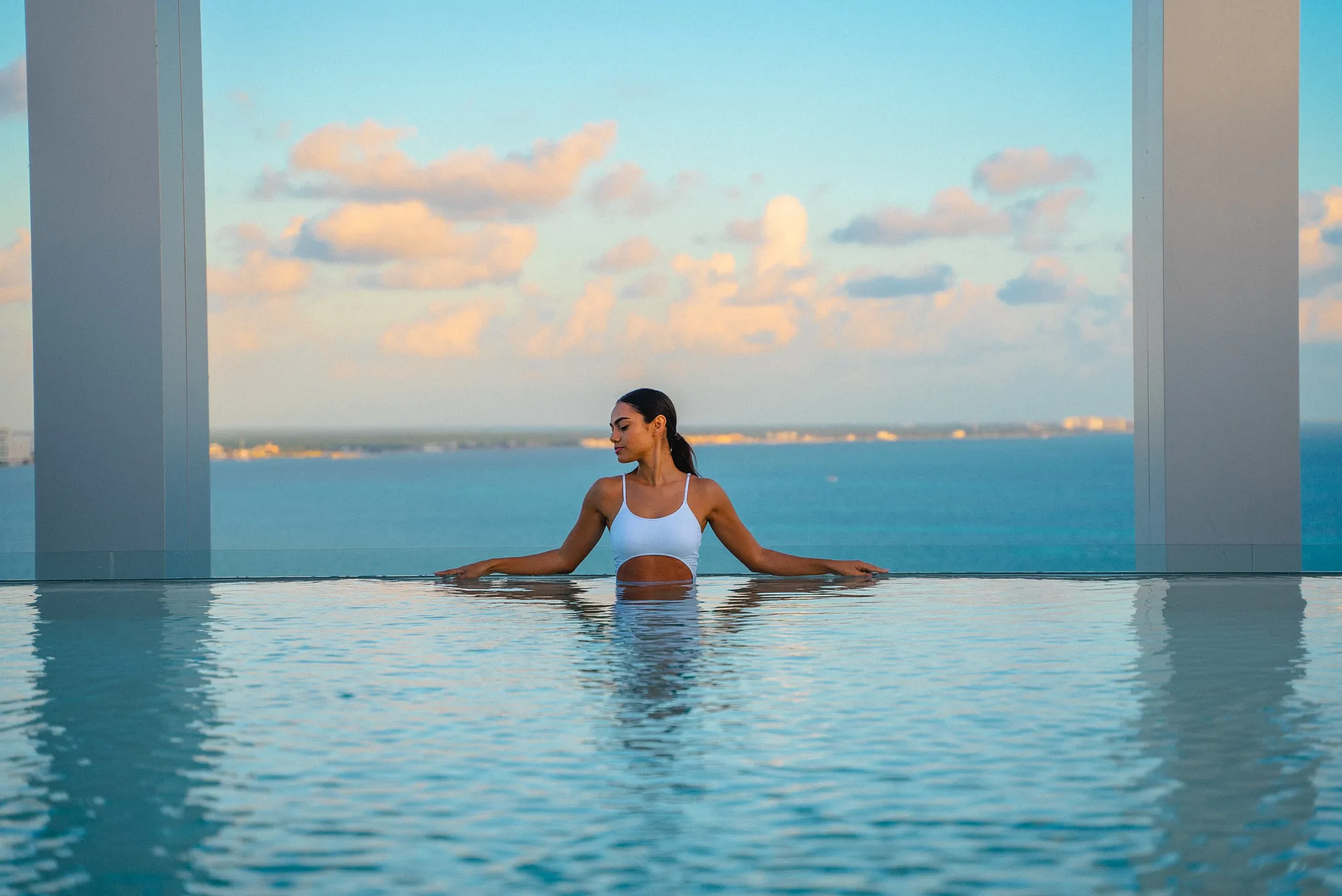 Woman relaxing in a rooftop infinity pool overlooking the ocean at Breathless Cancun Soul Resort in Cancun.