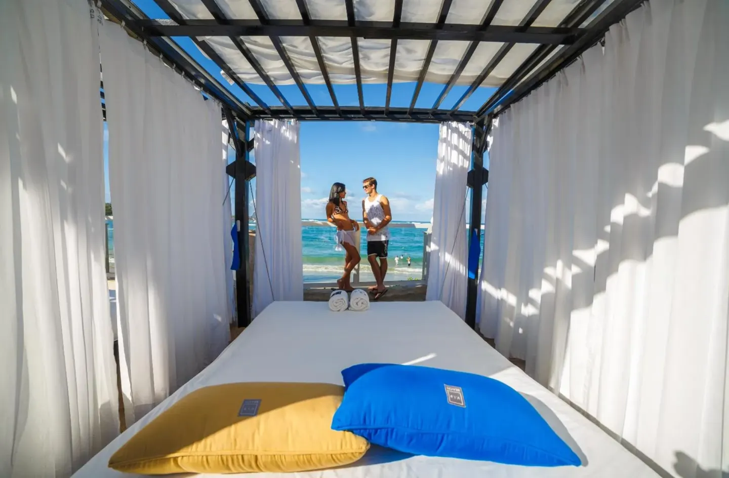 Beach cabana bed with white curtains and ocean beyond at Lifestyle Tropical Beach Resort & Spa.