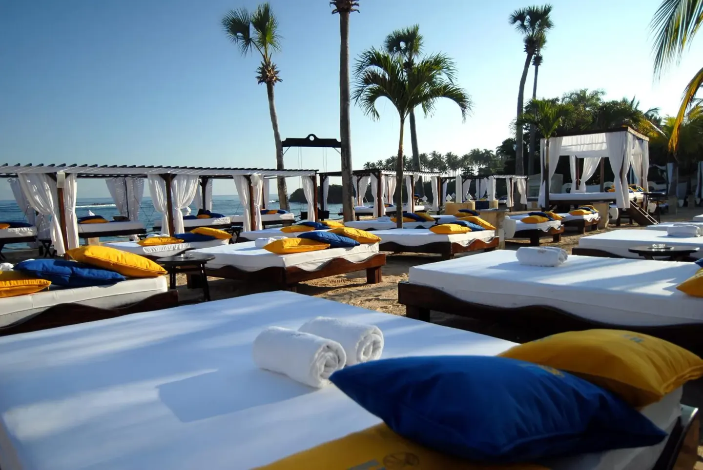 Beach daybeds with white linens and blue and yellow pillows at Lifestyle Tropical Beach Resort & Spa.