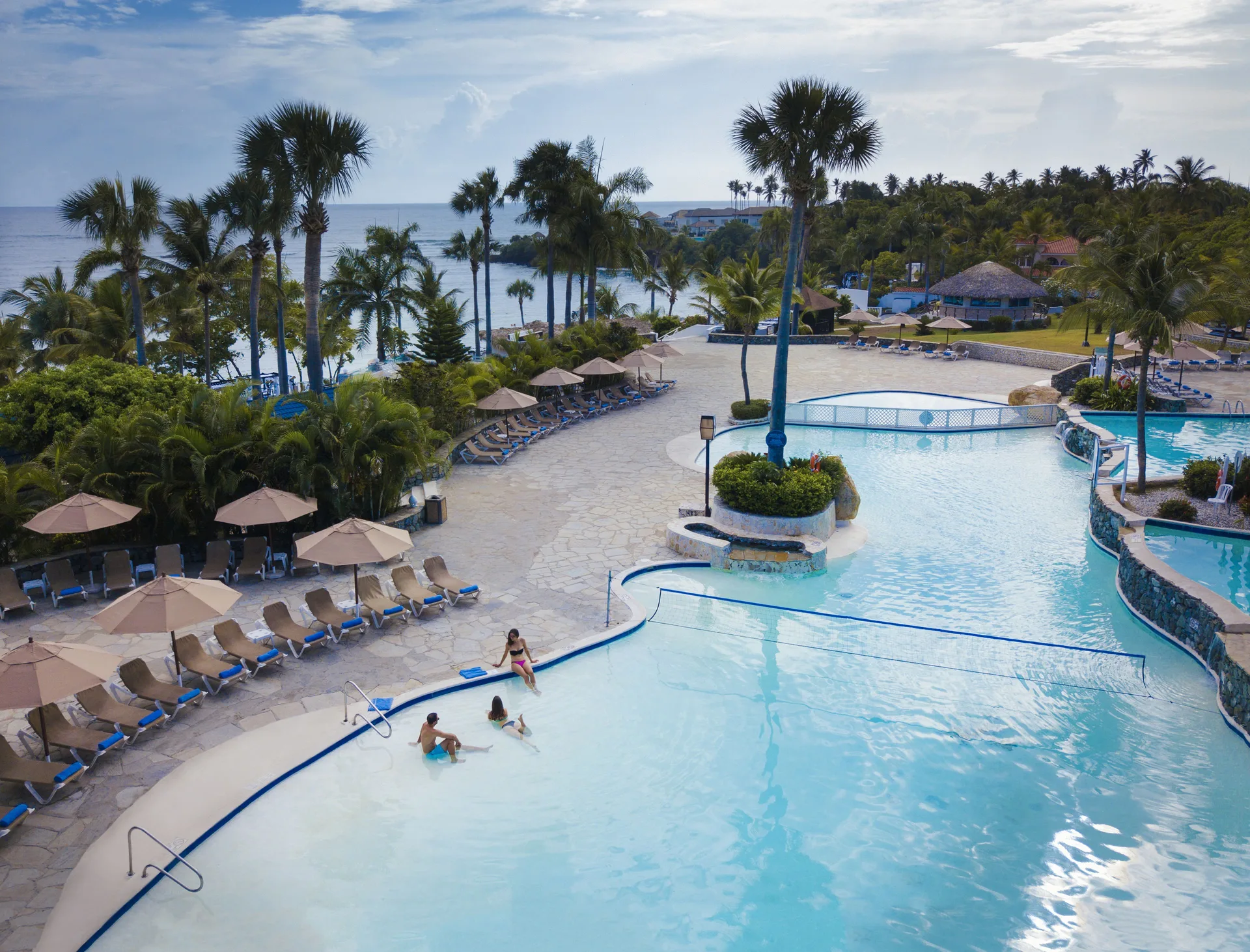 Large pool with loungers, palms and ocean beyond at Lifestyle Tropical Beach Resort & Spa.