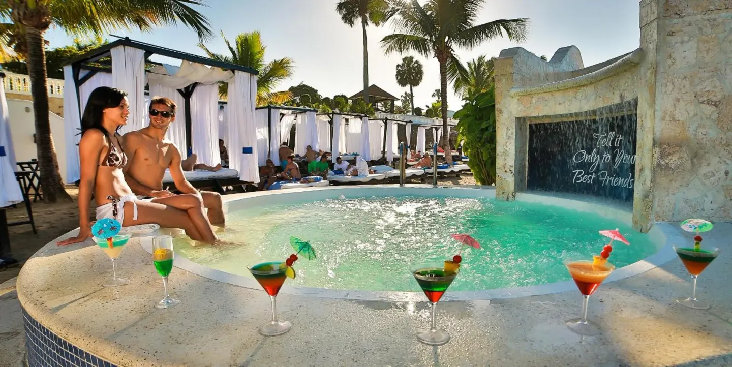 Couple sitting beside a small pool with cocktails at Lifestyle Tropical Beach Resort & Spa.