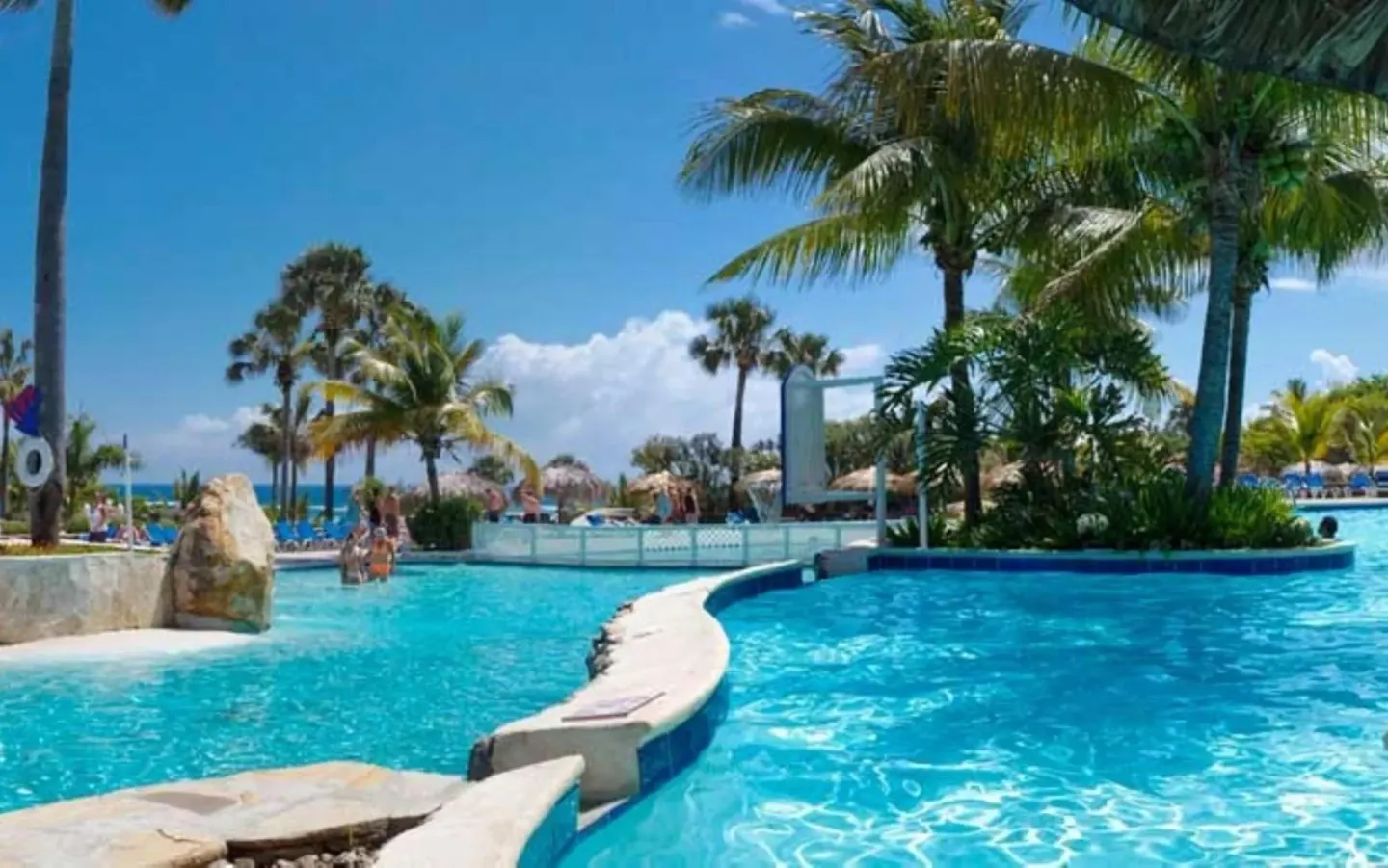 Curving pool with palms and ocean glimpses at Lifestyle Tropical Beach Resort & Spa.