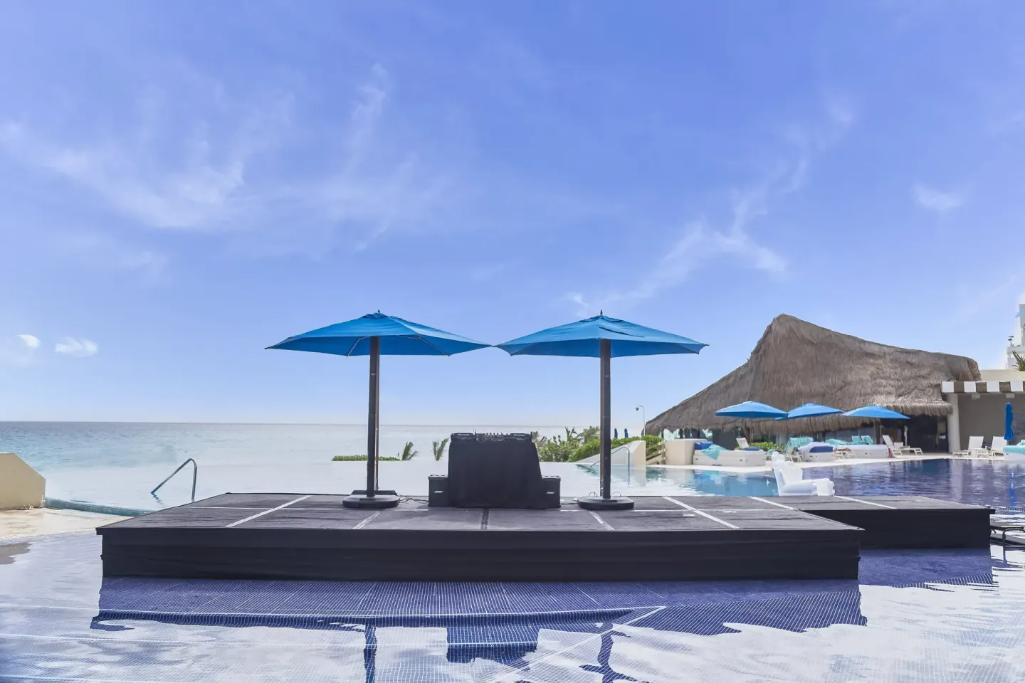 Beachfront pool deck with blue umbrellas and ocean view at Live Aqua Cancun.