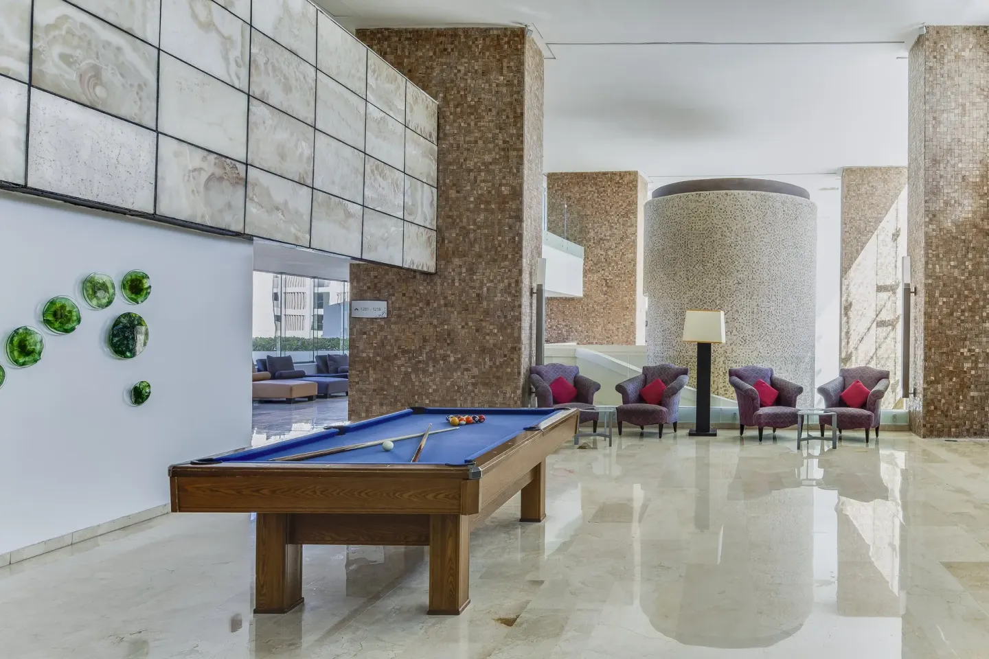Billiards table and lounge chairs in a bright indoor area at Live Aqua Cancun.