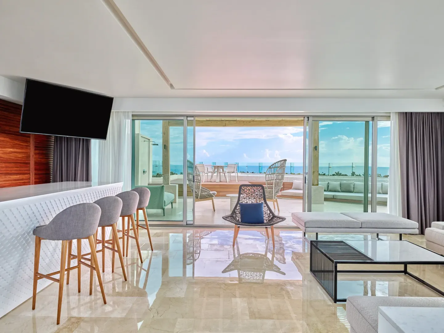Ocean-view suite living room with bar seating and terrace at Live Aqua Cancun.