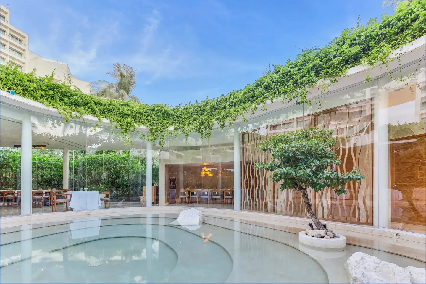 Reflecting pool courtyard beside glass-walled dining rooms at Live Aqua Cancun.
