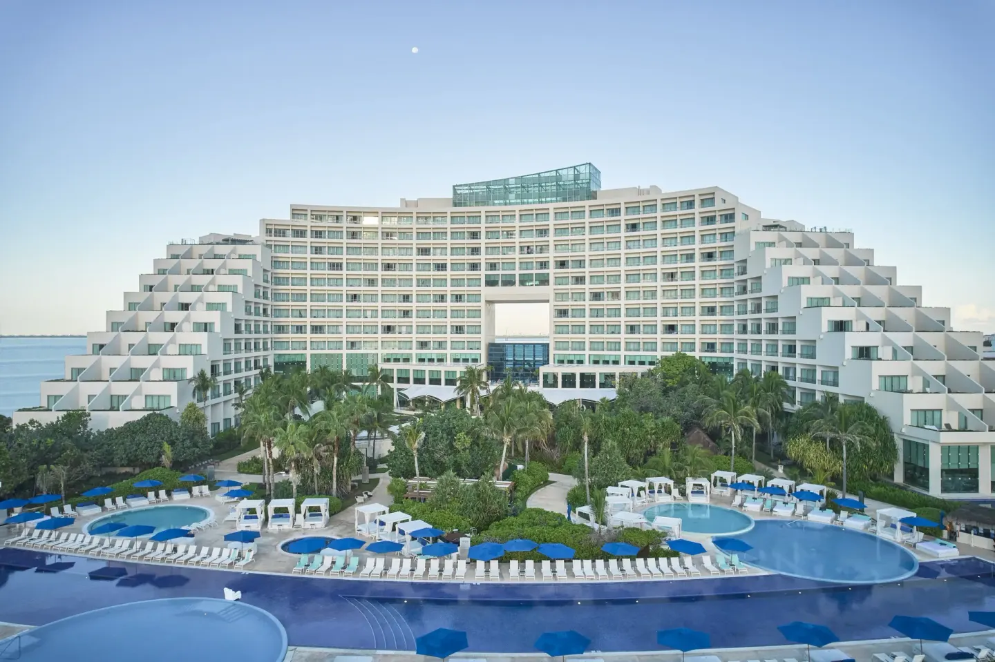 Resort exterior, pools, palms, and blue umbrellas at Live Aqua Cancun.