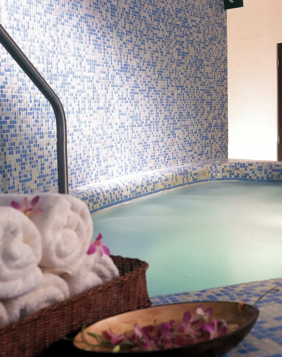 Spa pool with mosaic tile, rolled towels, and flowers at Live Aqua Cancun.