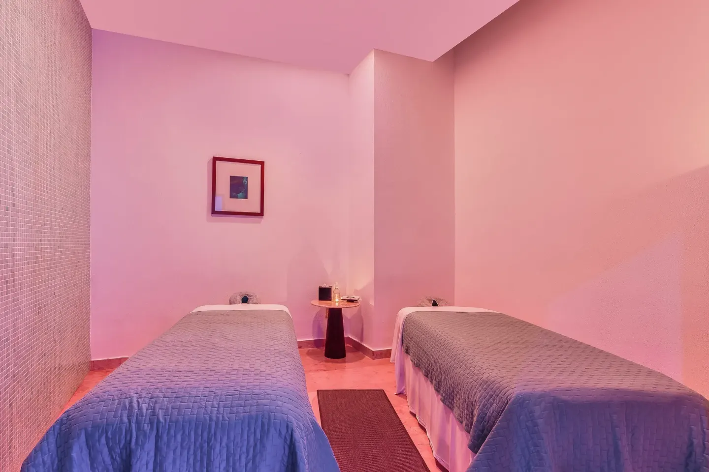 Two spa treatment beds in a pink-lit room at Live Aqua Cancun.