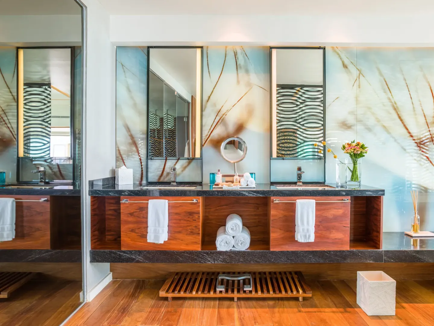 Bathroom vanity with mirrors and floral decor in a suite at Live Aqua Cancun.