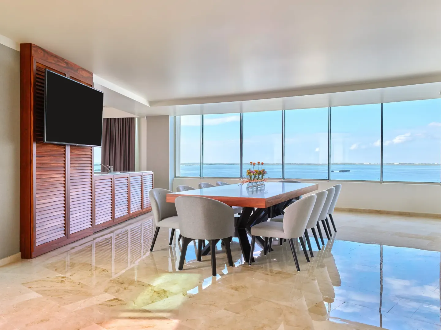 Suite dining table beside panoramic water-view windows at Live Aqua Cancun.