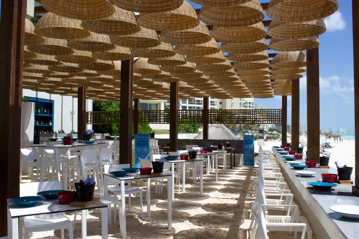 Beachside taco stand seating with woven shades at Live Aqua Cancun.