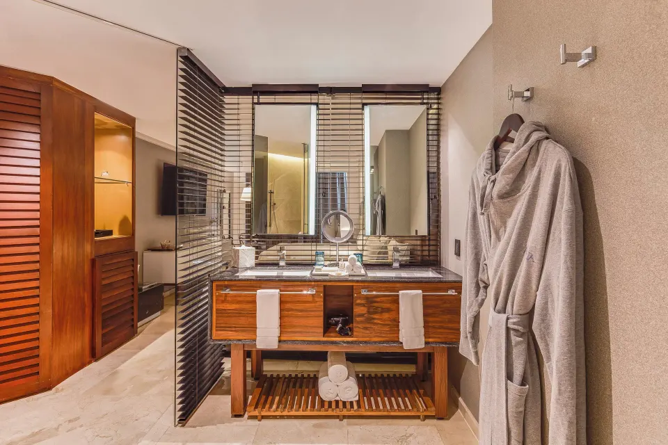Premium Room bathroom with wood vanity, robes, and glass partitions at Live Aqua Cancun.