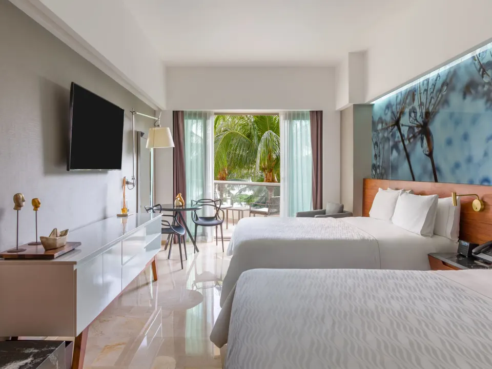 Premium Room with two beds, balcony doors, and garden palms at Live Aqua Cancun.