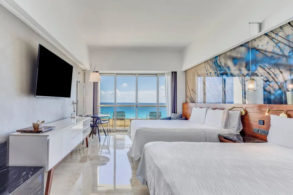 Two-bed oceanfront premium room with glass balcony doors at Live Aqua Cancun.