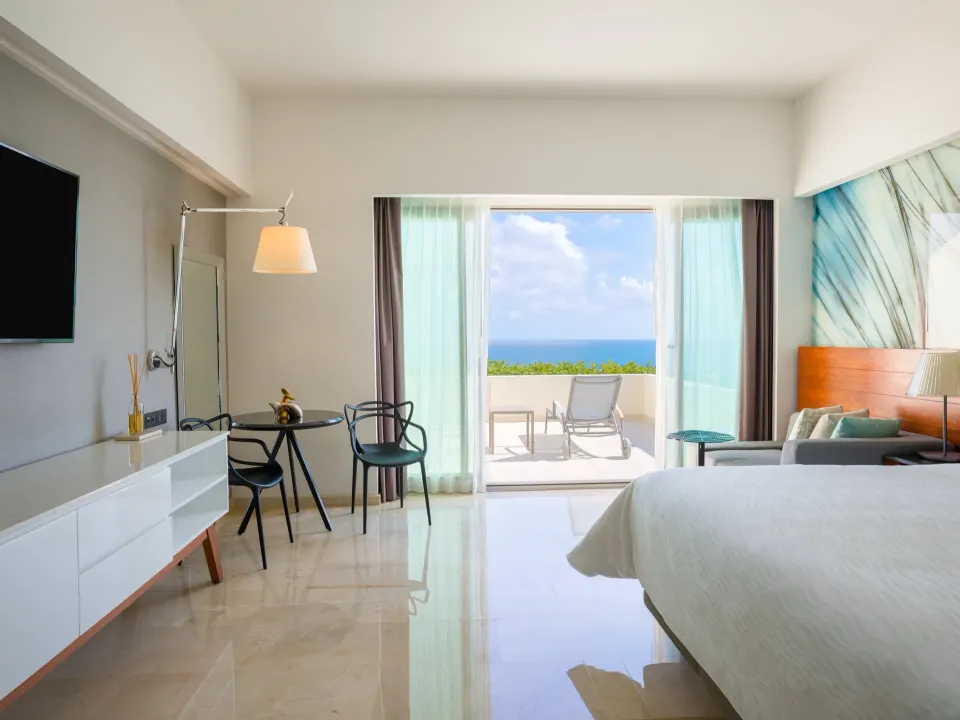 Premium Room king bed with dining table and open terrace doors at Live Aqua Cancun.
