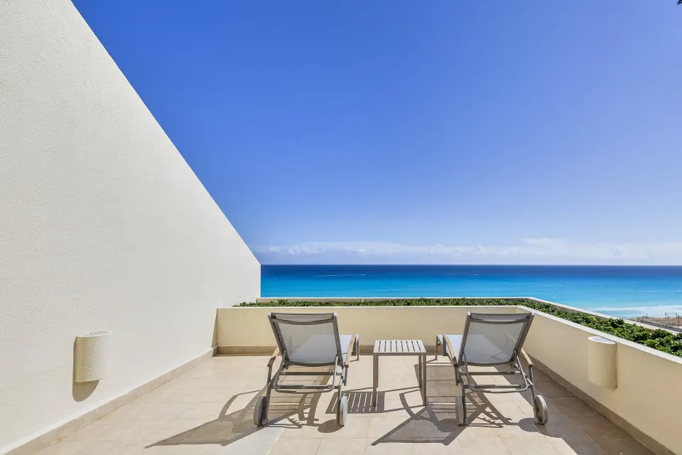 Oceanfront terrace with two loungers, a small table, and turquoise water at Live Aqua Cancun.
