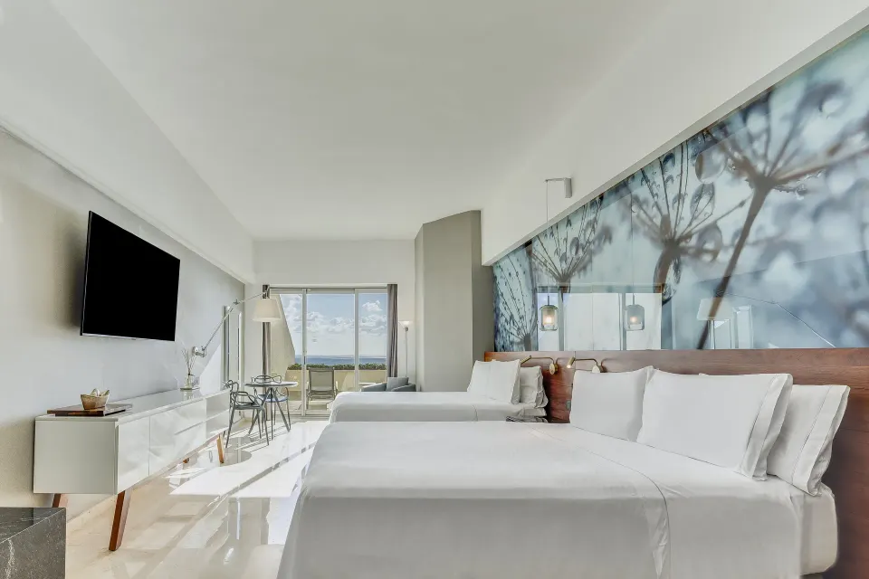 Premium Room with two beds, wall mural, TV, and oceanfront terrace at Live Aqua Cancun.