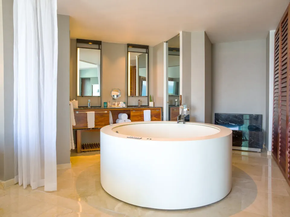 Round jetted tub and double vanity in an oceanfront suite bathroom at Live Aqua Cancun.