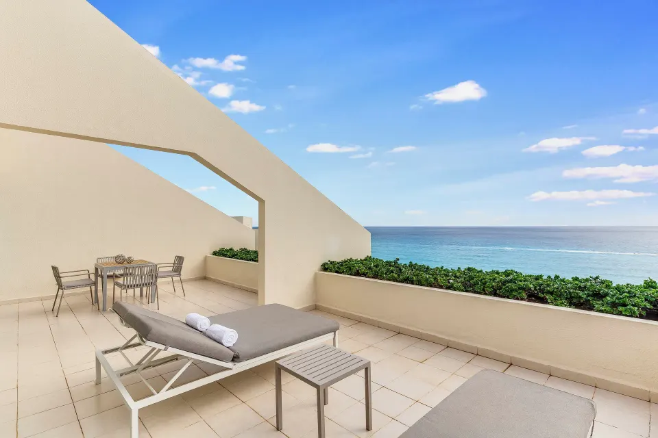 Oceanfront suite terrace with loungers, dining table, and sea view at Live Aqua Cancun.