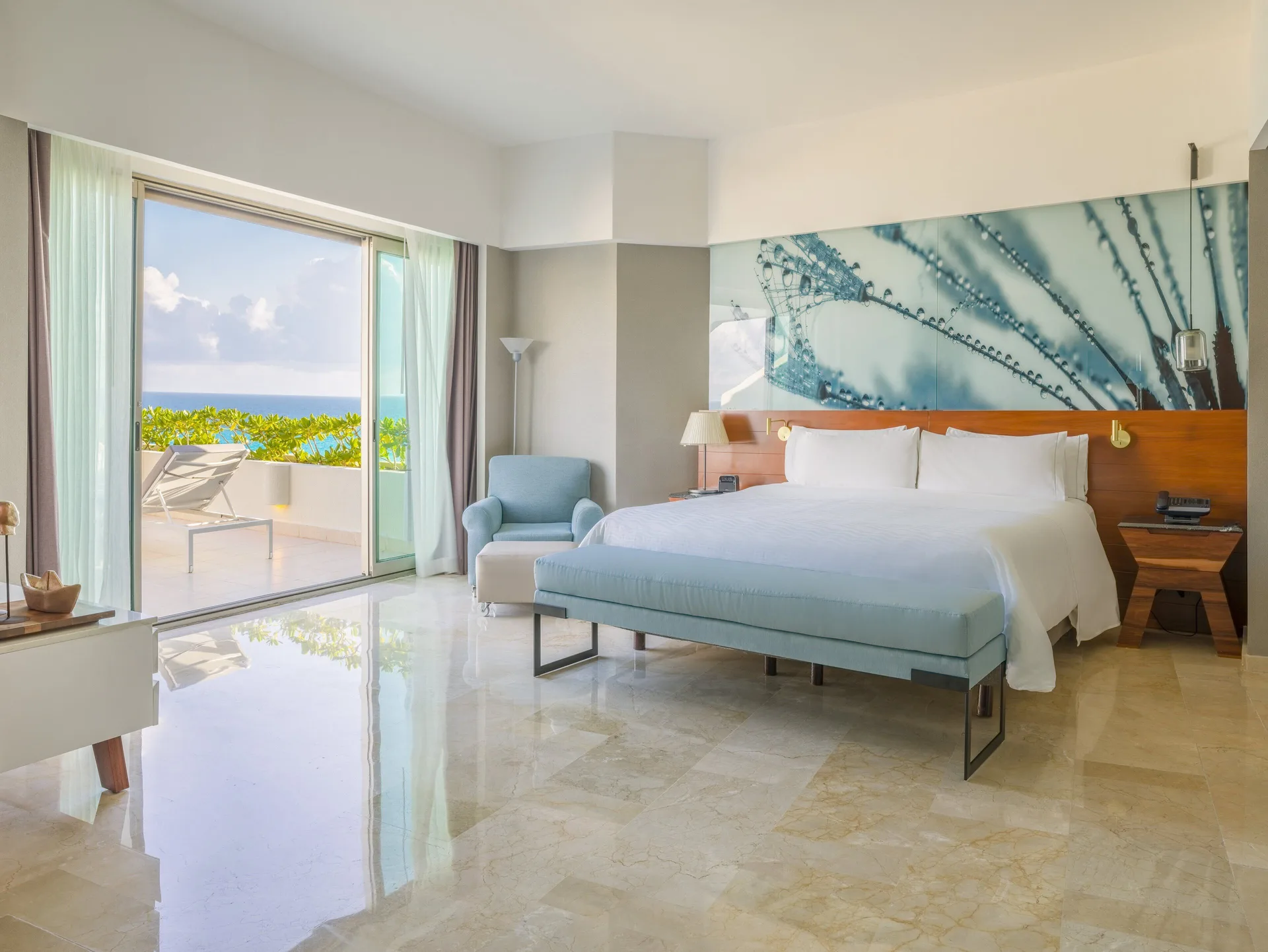 Oceanfront suite king bed with balcony and lounge chair at Live Aqua Cancun.