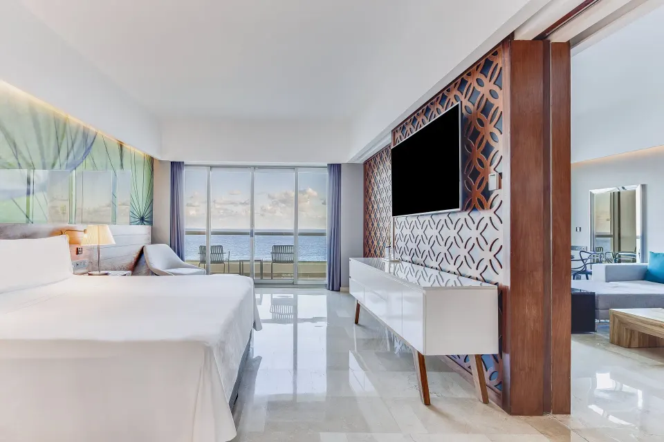 King bed, balcony, ocean view, and TV divider in a suite at Live Aqua Cancun.