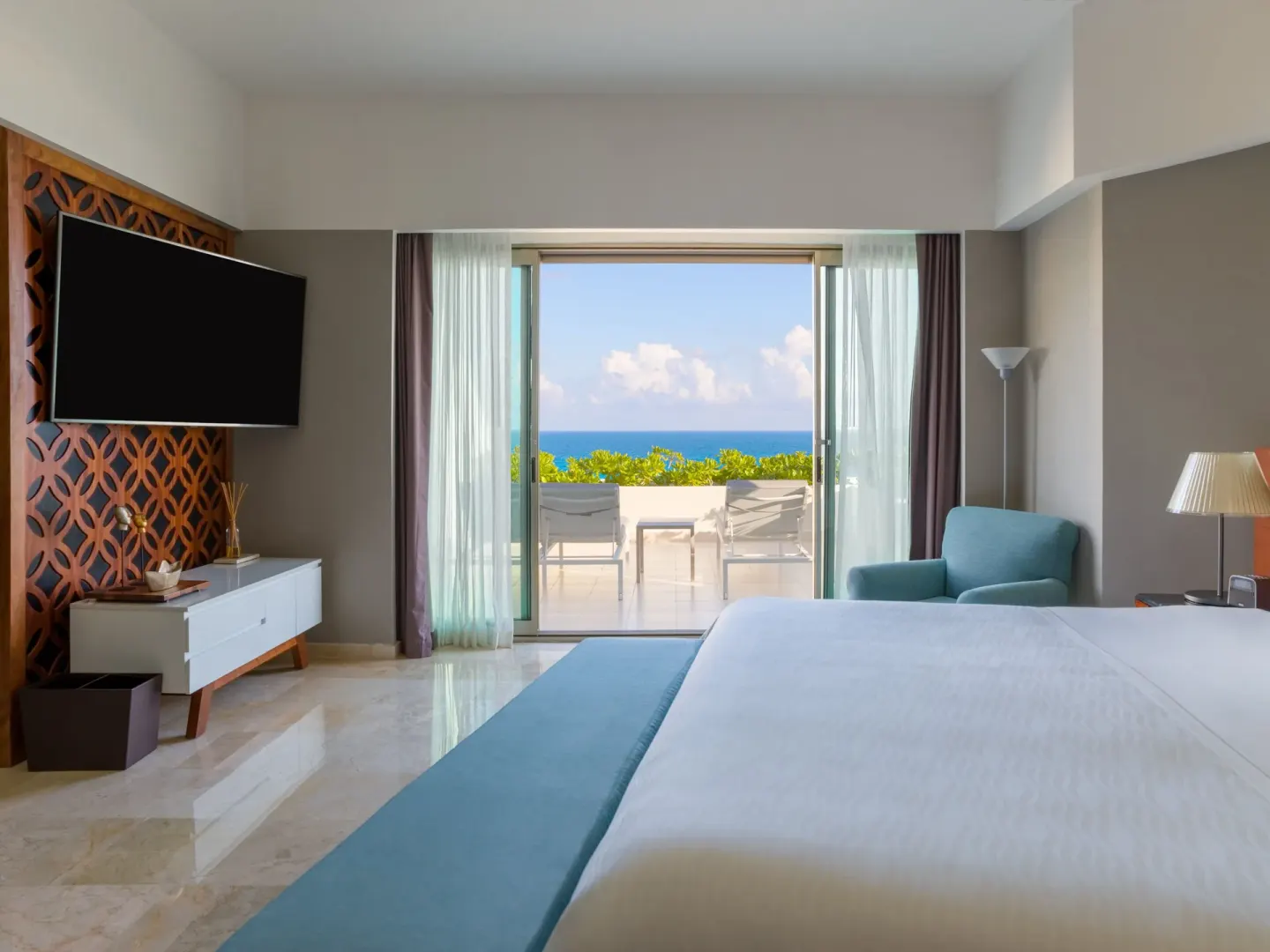 King bed facing a terrace with lounge chairs and ocean view at Live Aqua Cancun.