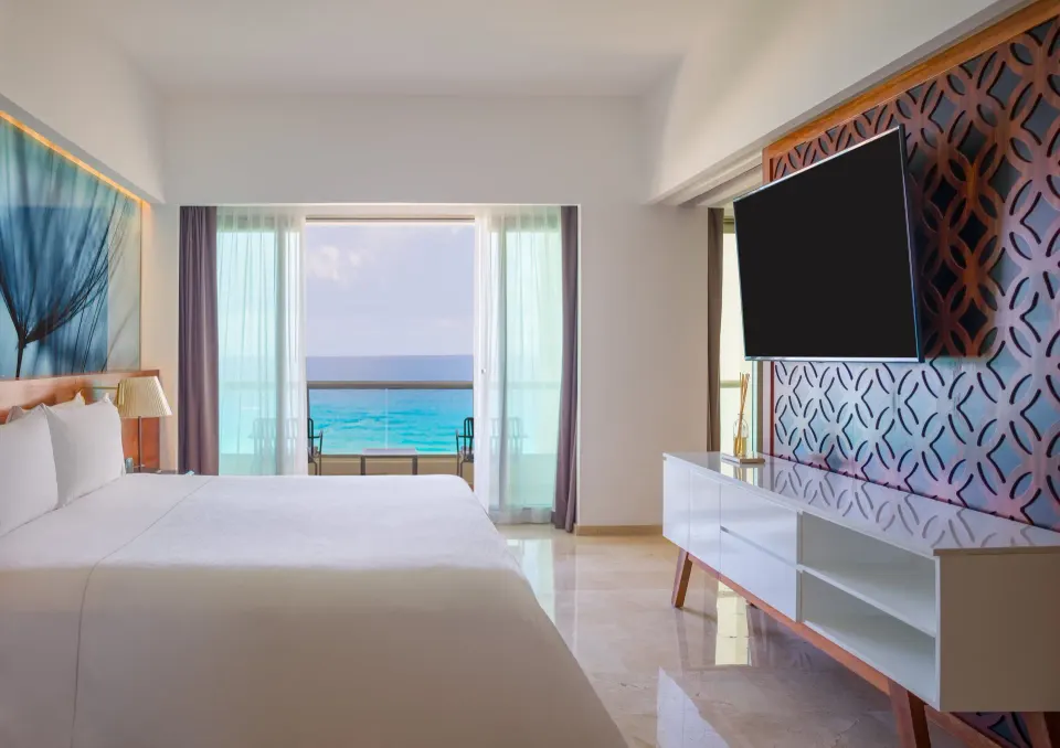 Viento Suite king bed with TV wall and ocean-view balcony at Live Aqua Cancun.
