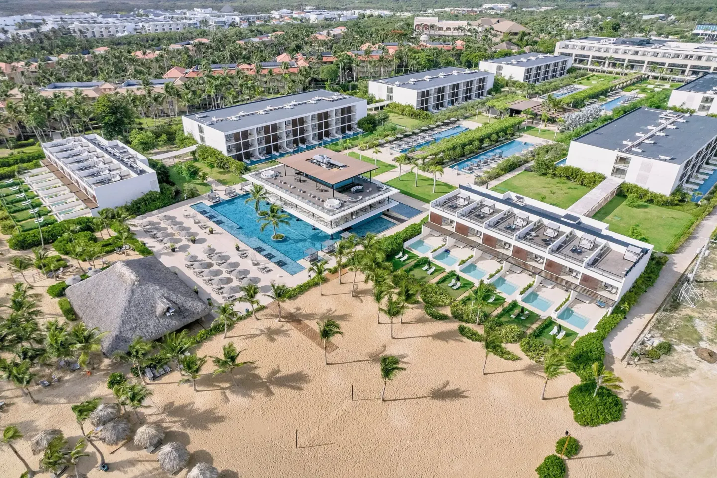 Aerial view of beachfront pools, palms, and resort buildings at Live Aqua Punta Cana.
