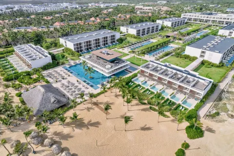 Aerial view of beachfront pools, palms, and resort buildings at Live Aqua Punta Cana.