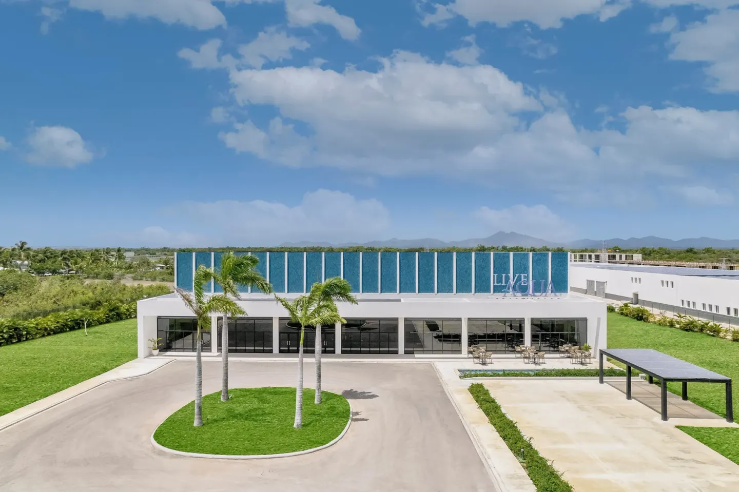 Exterior building with palms and Live Aqua Punta Cana signage at Live Aqua Punta Cana.