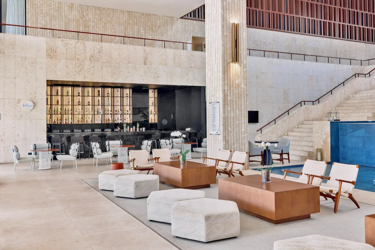Open lobby lounge with bar, sofas and staircase at Live Aqua Punta Cana.