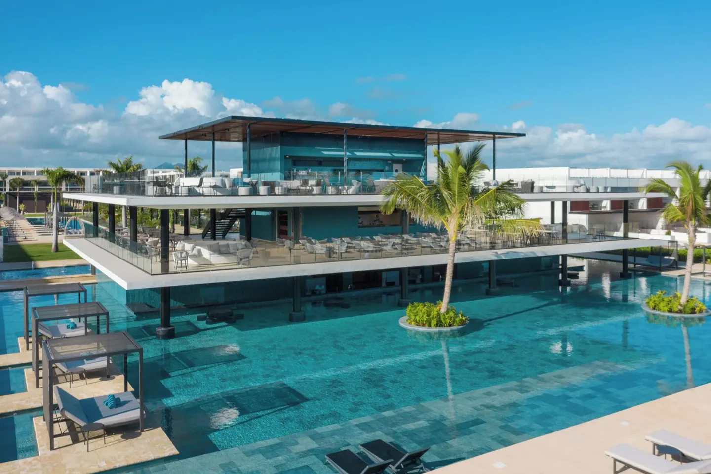 Modern pool area with a two-level terrace and palm trees at Live Aqua Punta Cana.