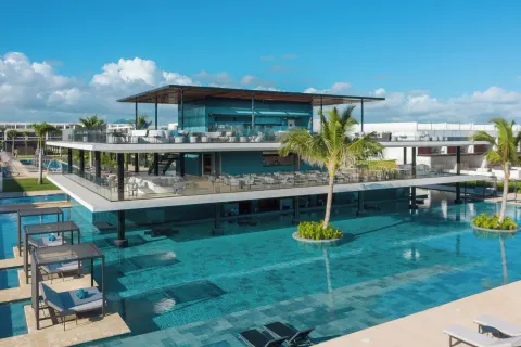 Modern pool area with a two-level terrace and palm trees at Live Aqua Punta Cana.