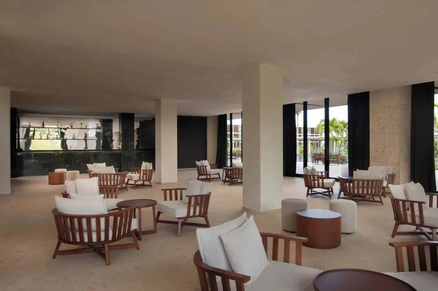 Open lounge seating area with cushioned wooden chairs at Live Aqua Punta Cana.