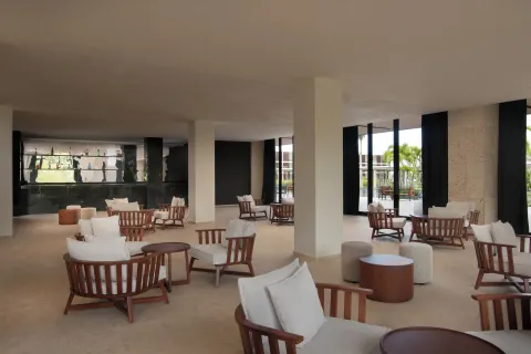 Open lounge seating area with cushioned wooden chairs at Live Aqua Punta Cana.