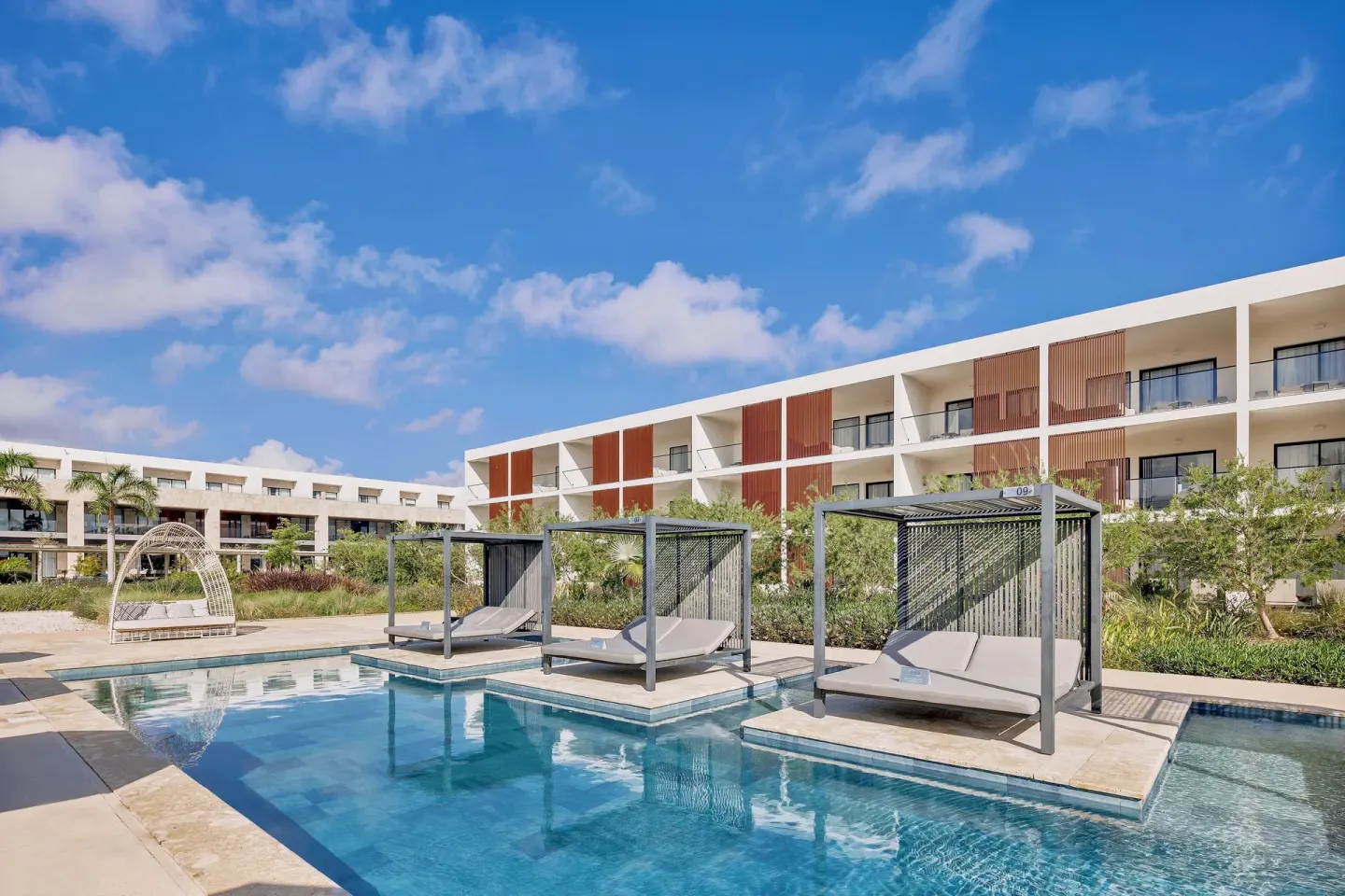 Pool islands with shaded daybeds and resort buildings at Live Aqua Punta Cana.