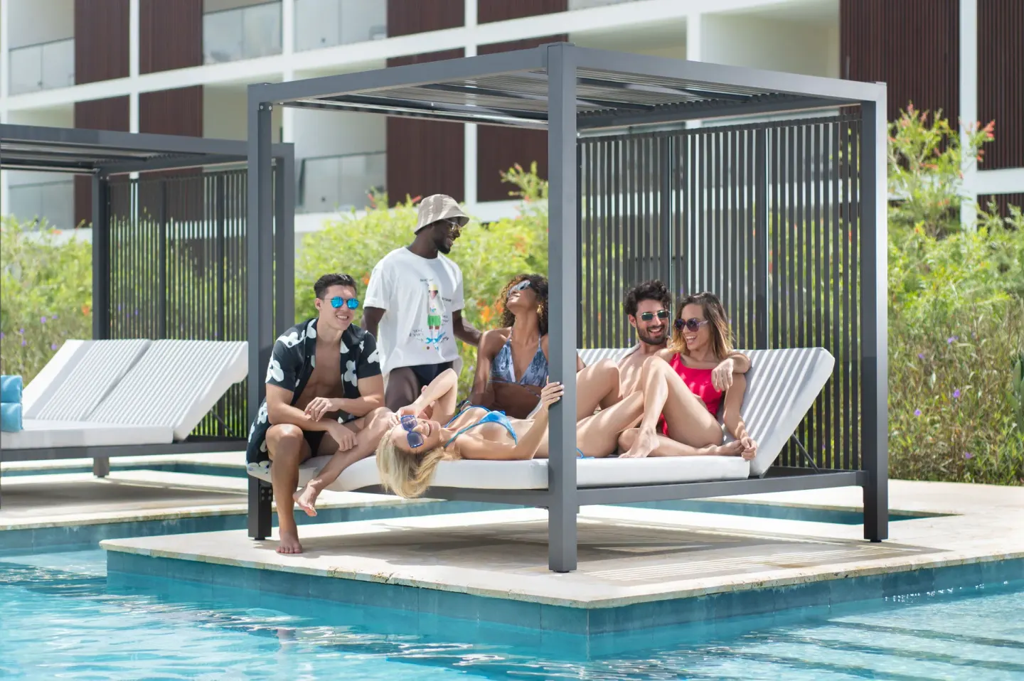 Guests relax on shaded pool cabanas beside the water at Live Aqua Punta Cana.