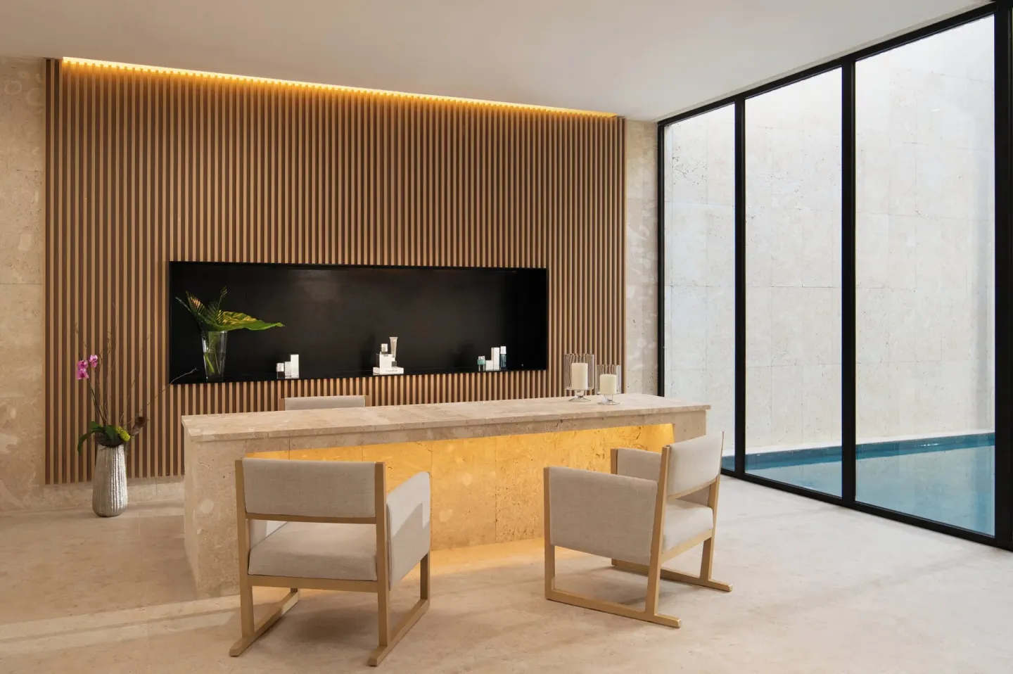 Spa reception desk with chairs beside a glass-walled pool at Live Aqua Punta Cana.