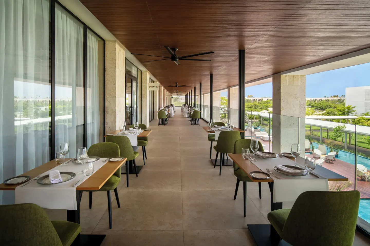 Outdoor terrace tables overlooking pools and greenery at Live Aqua Punta Cana.