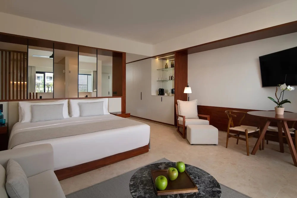 Junior Suite king bed with seating and desk area at Live Aqua Punta Cana.