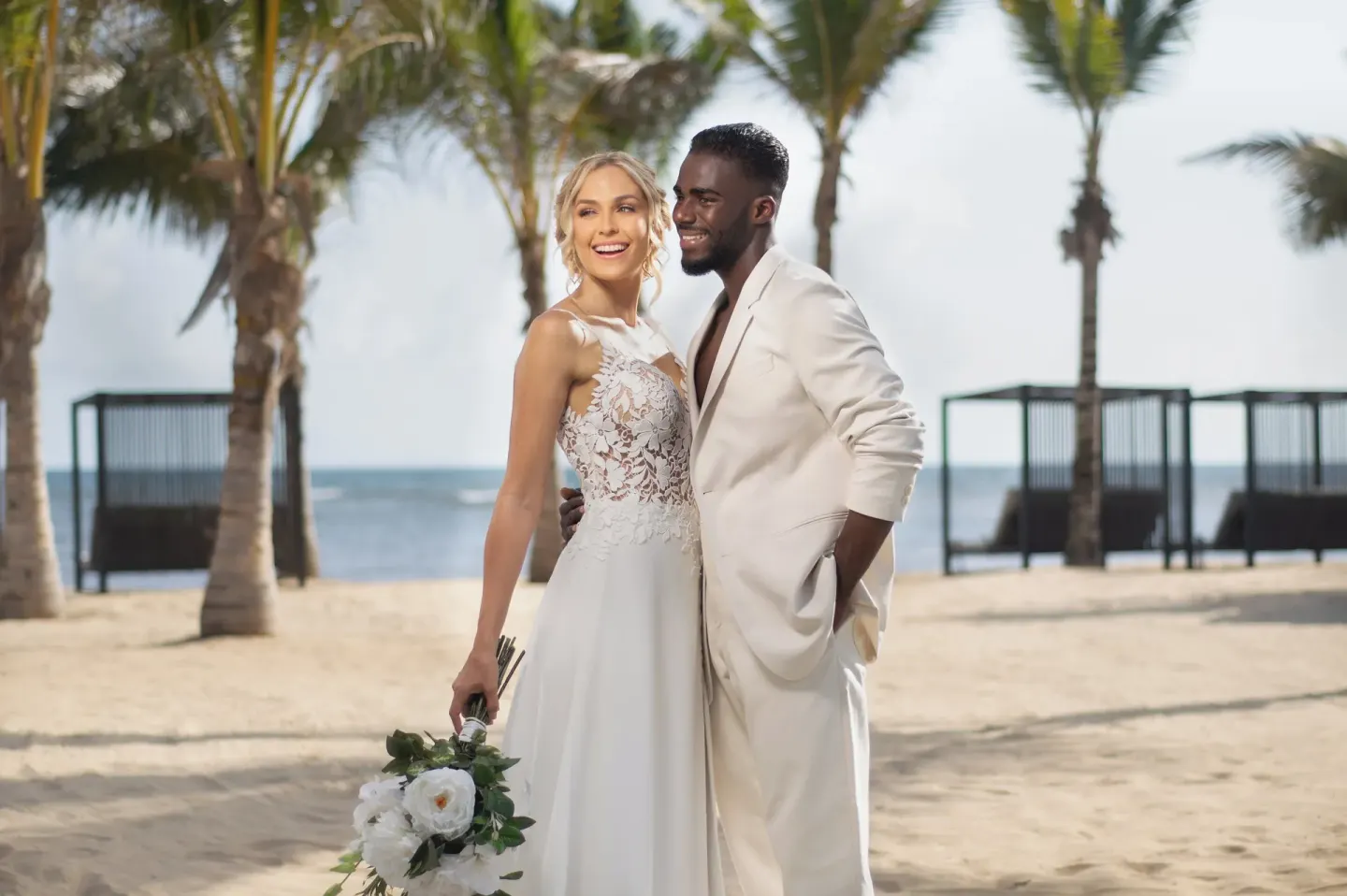 Wedding couple posing on the beach with palms behind them at Live Aqua Punta Cana.