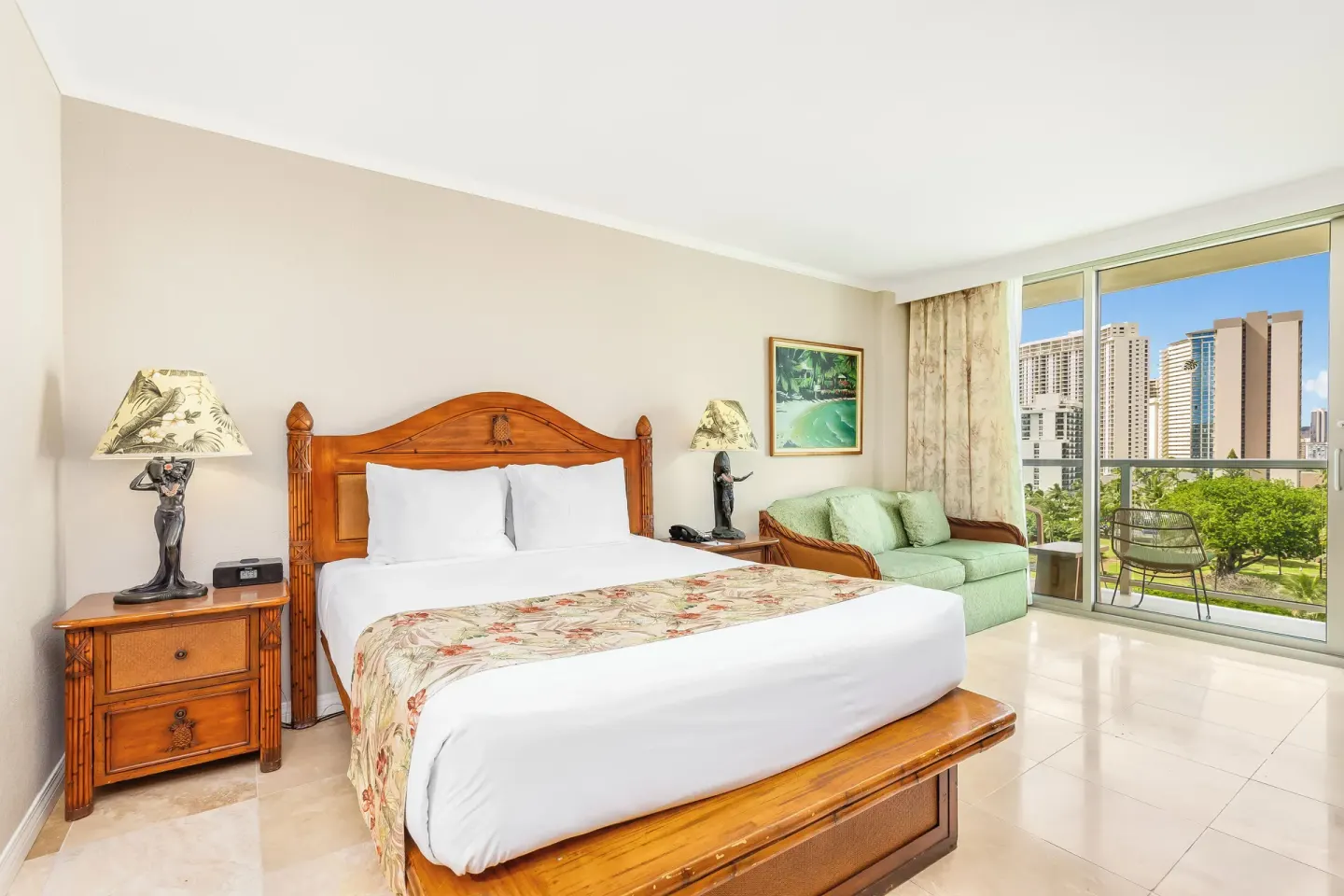 King-bed guest room with sofa, balcony, and city views at Luana Waikiki Hotel & Suites.