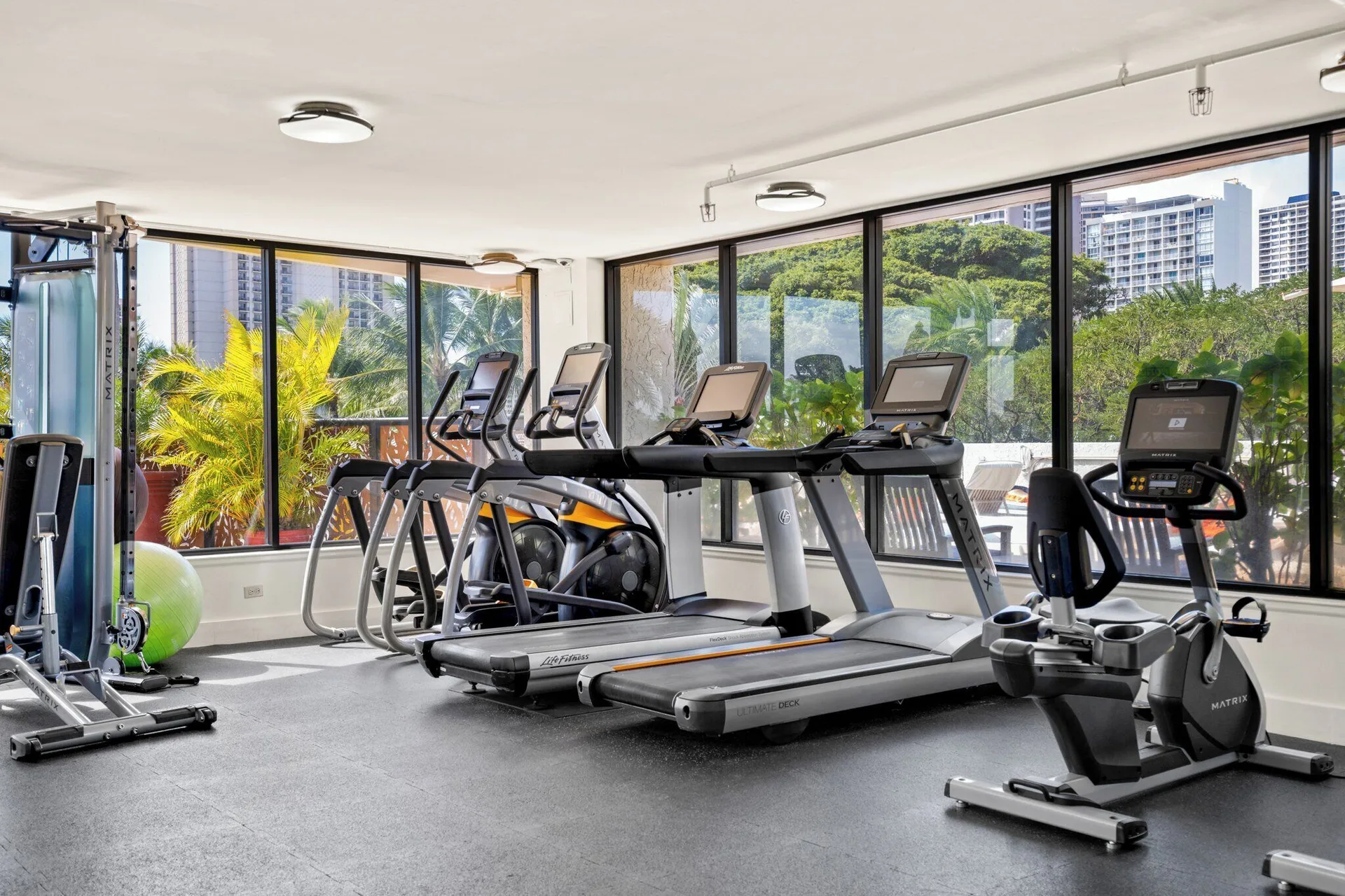 Fitness room with cardio equipment and large windows at Luana Waikiki Hotel & Suites.