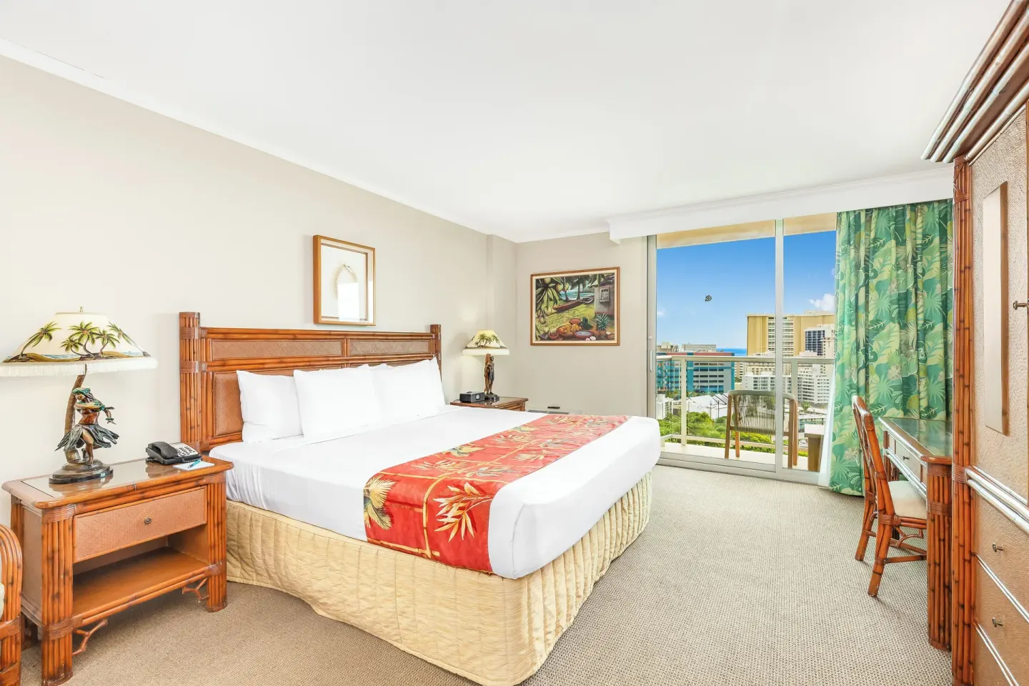 King-bed guest room with desk and balcony at Luana Waikiki Hotel & Suites.