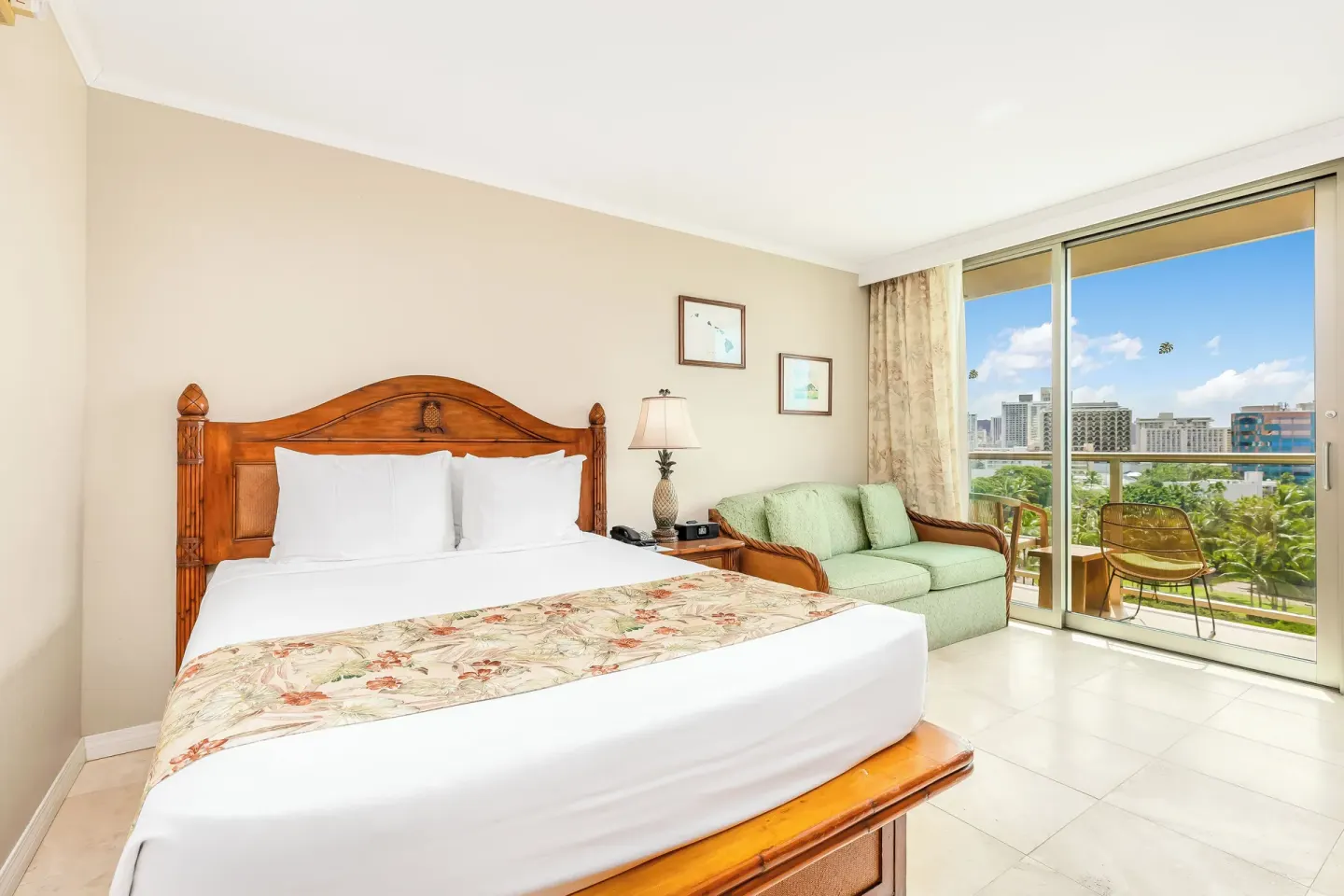 King-bed guest room with sofa and balcony view at Luana Waikiki Hotel & Suites.