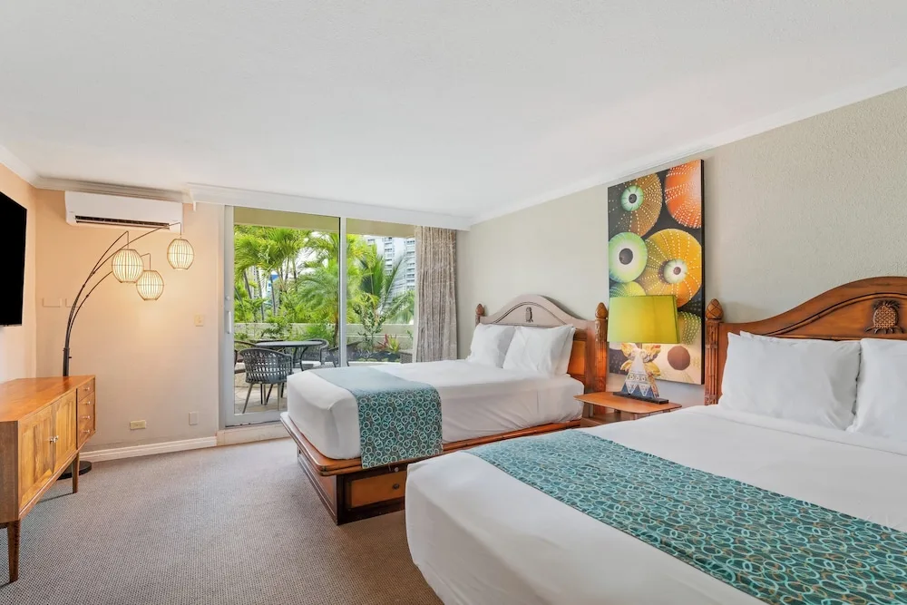 Two-bed guest room with tropical lanai view at Luana Waikiki Hotel & Suites.