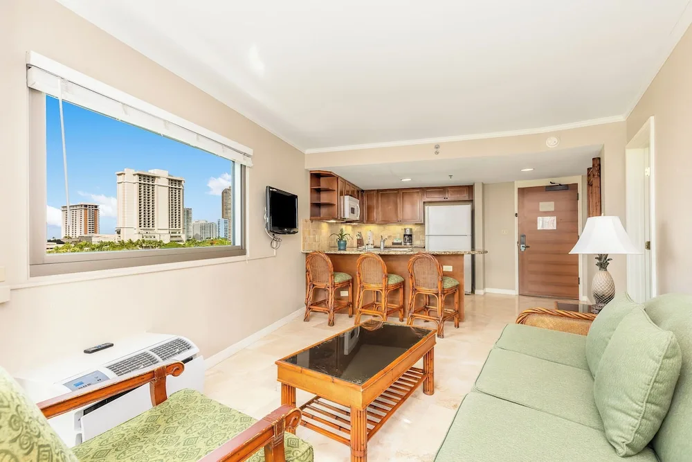 A living area with kitchenette and city view is shown at Luana Waikiki Hotel & Suites.