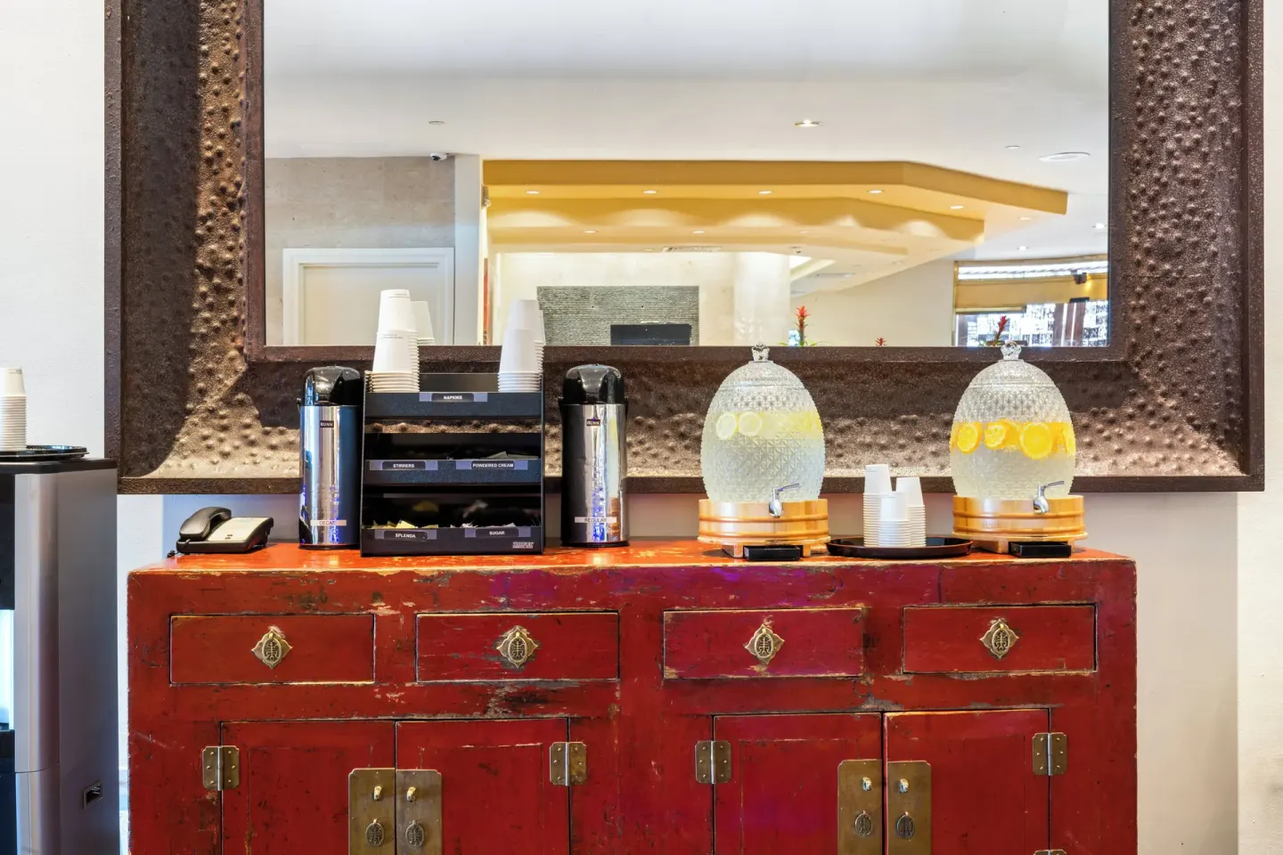 Close-up of the lobby drink station at Luana Waikiki Hotel & Suites with cups and dispensers.